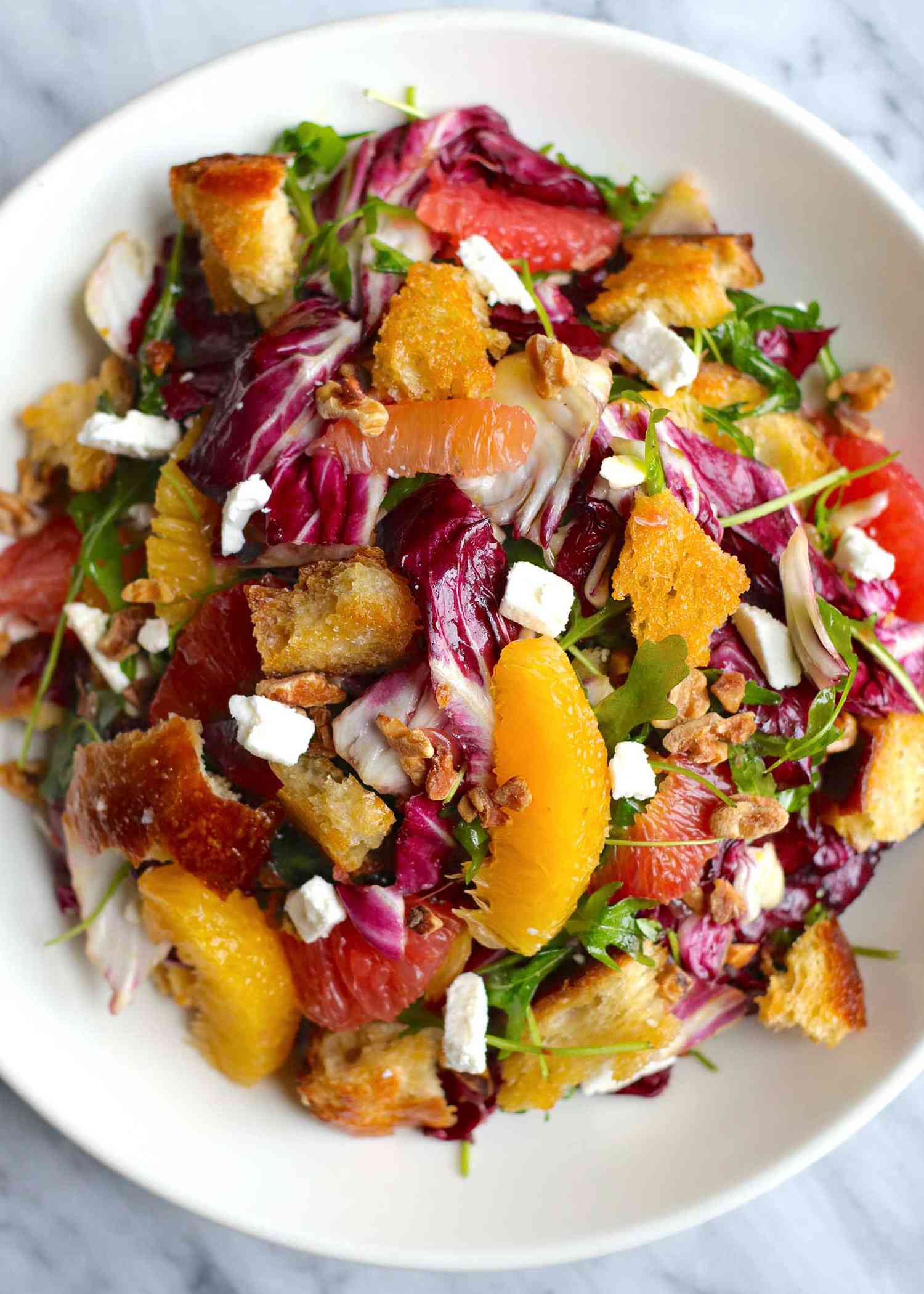 Citrus Salad on a white plate with orange and grapefruit, radicchio, croutons and feta cheese crumbles are visible.