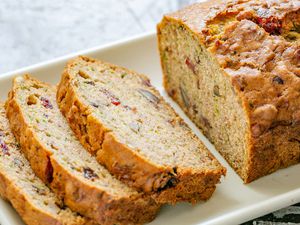 A sliced loaf of zucchini bread with dried cranberries
