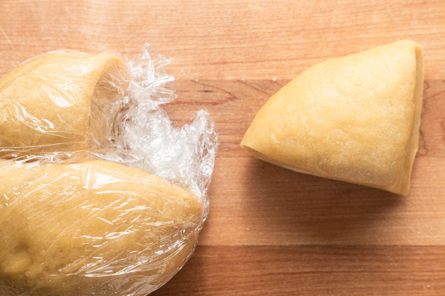 Homemade Tagliatelle Dough Cut Into Quarters and Covered With Plastic Wrap. One Quarter Removed From Plastic Wrap, Ready to Use