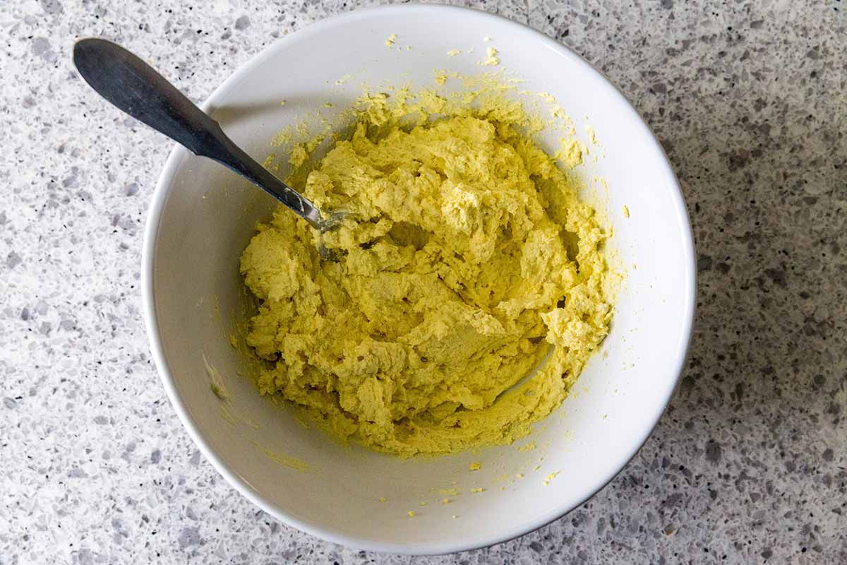 Best Deviled Eggs with Dill -- egg yolks stirred together in a white bowl with a spoon