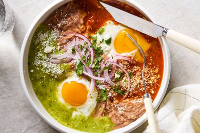 A white bowl with Huevos Divorciados, with a fork cutting into one of the egg yolks