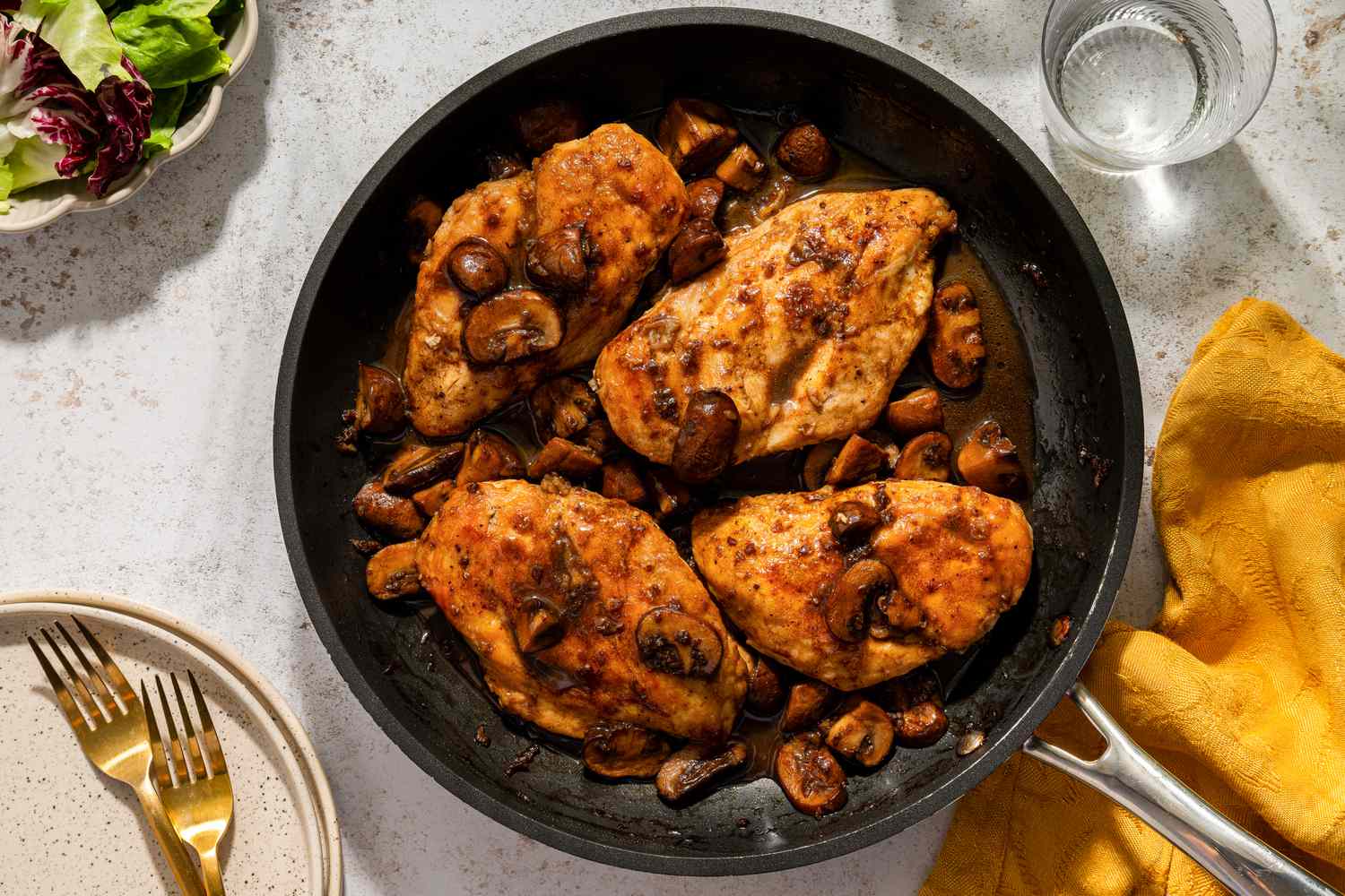 Four chicken breasts with balsamic mushrooms in a frying pan