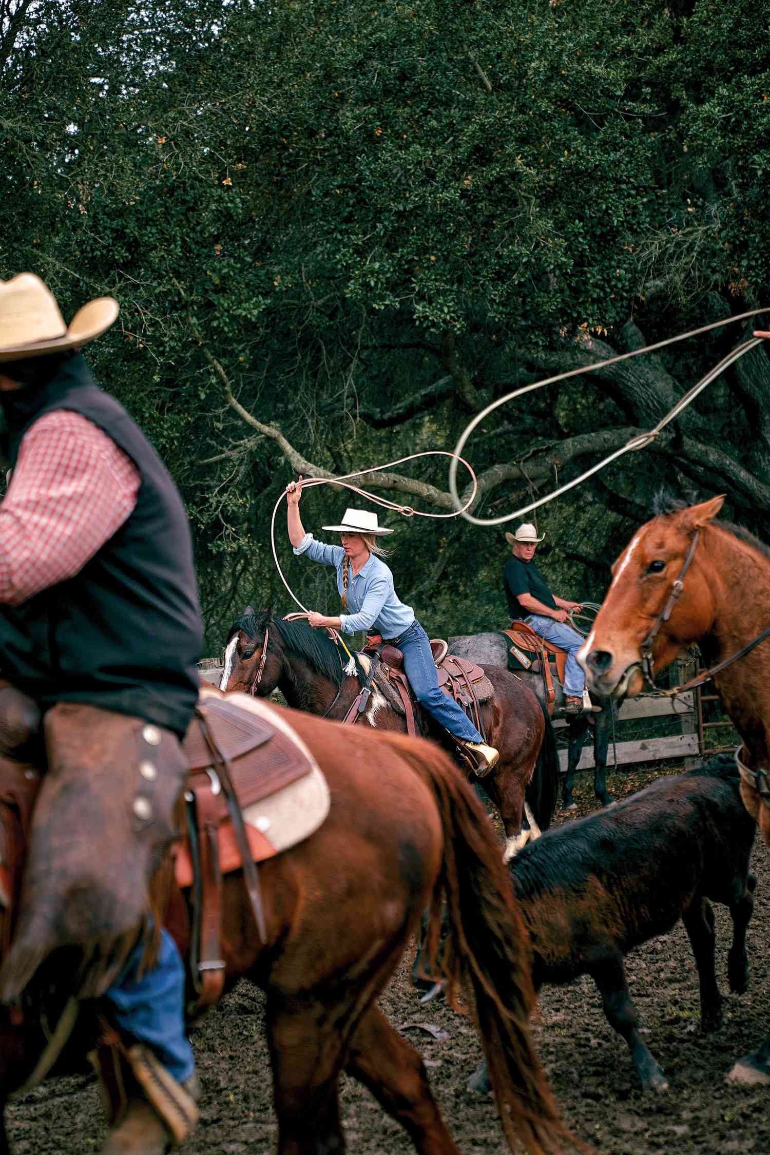 People riding horses on a ranch while swinging a lasso