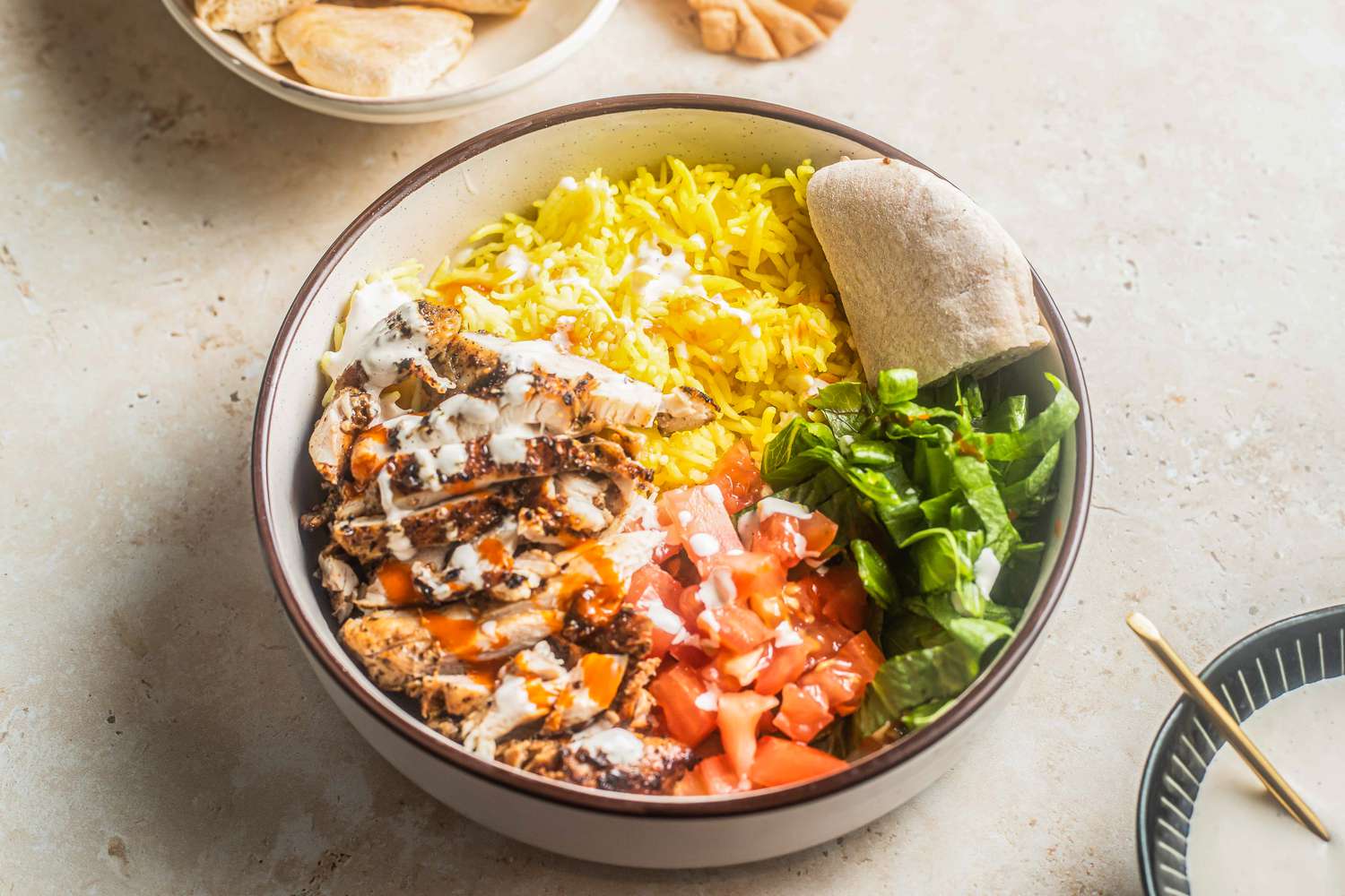  Bowl of Halal Cart-Style Chicken Over Rice Next a Bowl of Dressing and Another Bowl With Another Serving
