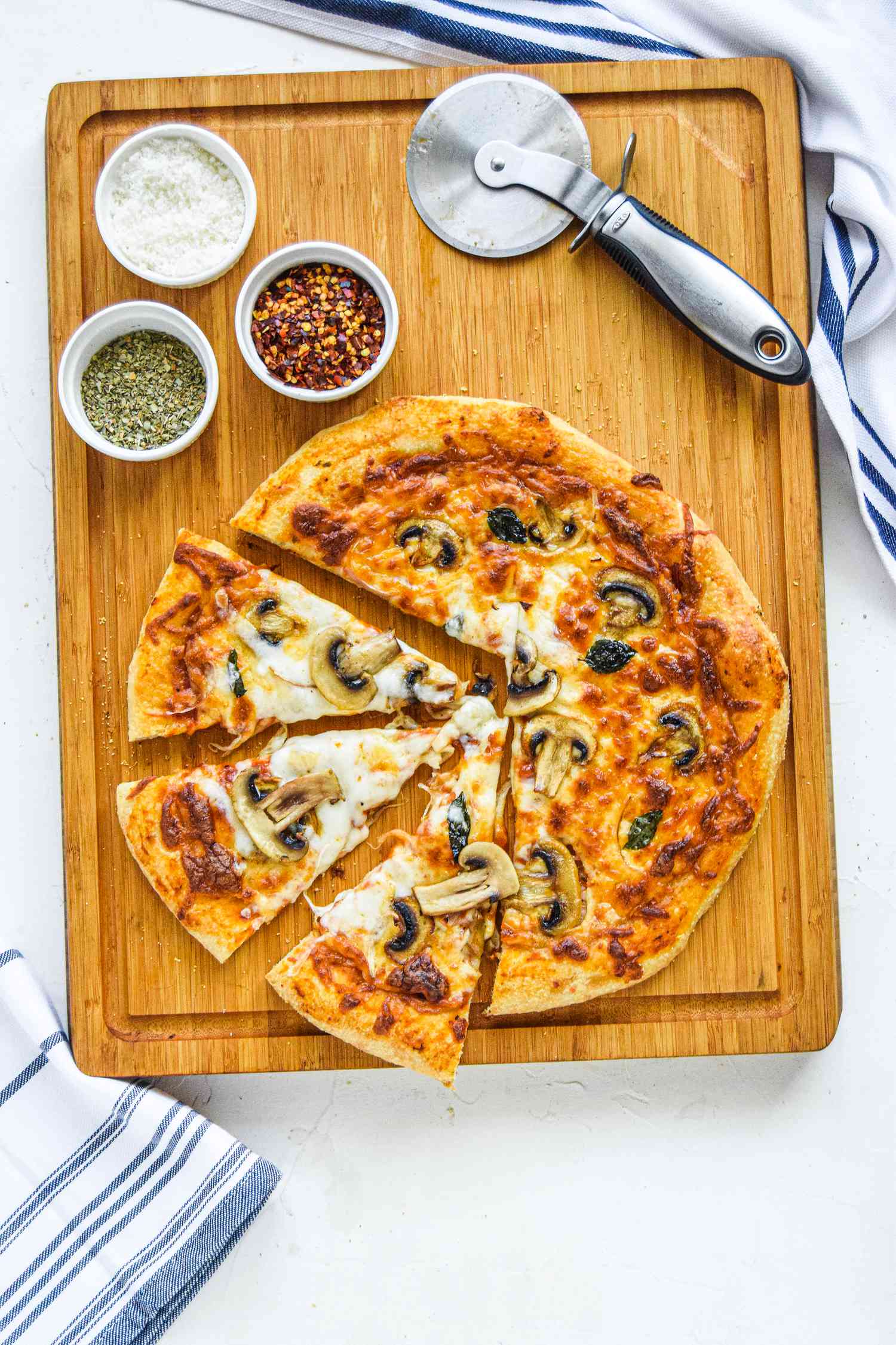 Overhead view of a pizza dough recipe and topped with cheese and mushrooms.