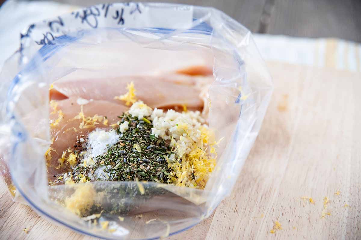 Easy Chicken Freezer Meal with Boneless Skinless Chicken Breast-plastic bag wtih chicken, herbs, and lemon zest