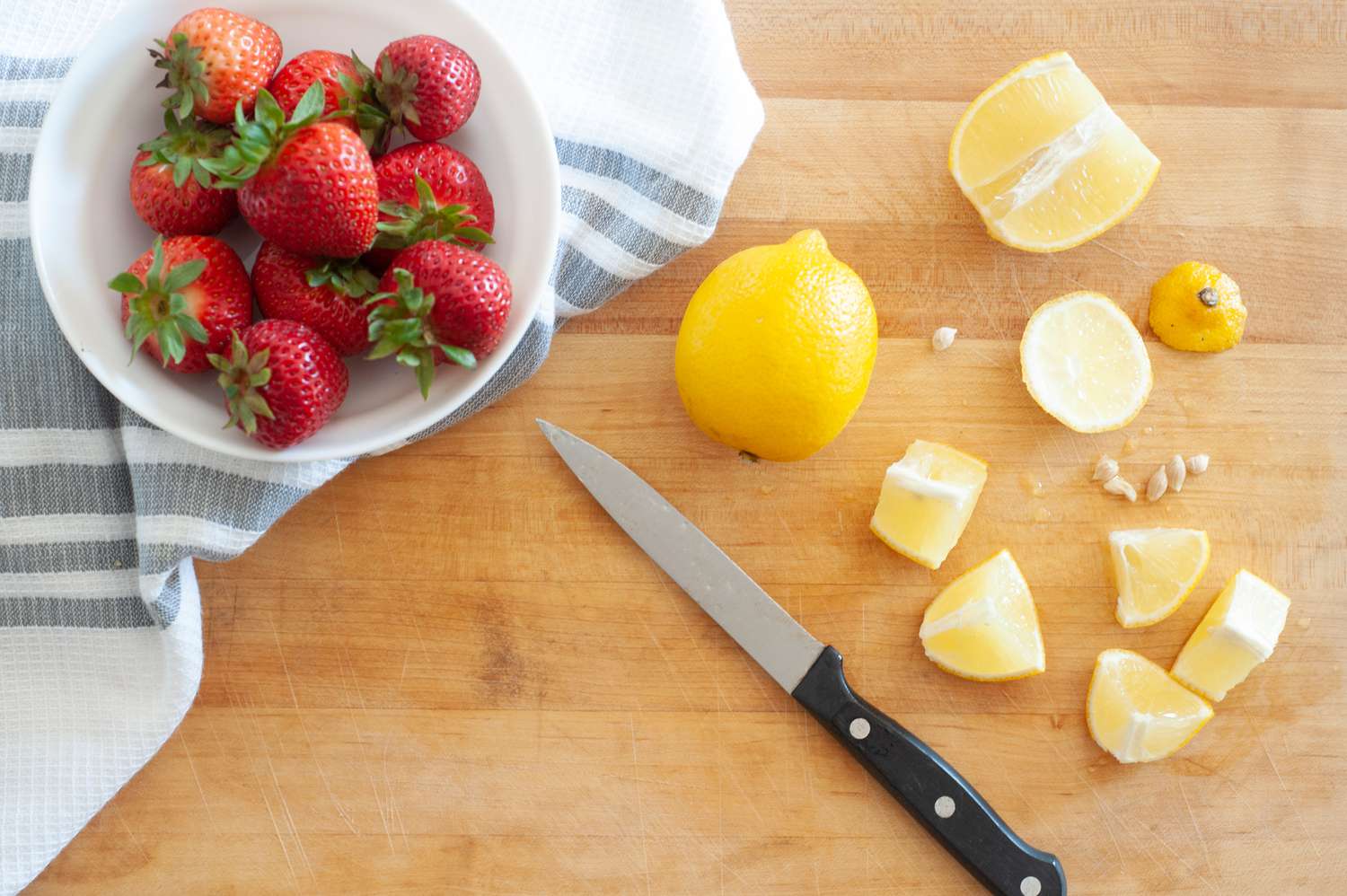 Chopped lemons and whole strawberries on a cutting board to make homemade strawberry lemonade