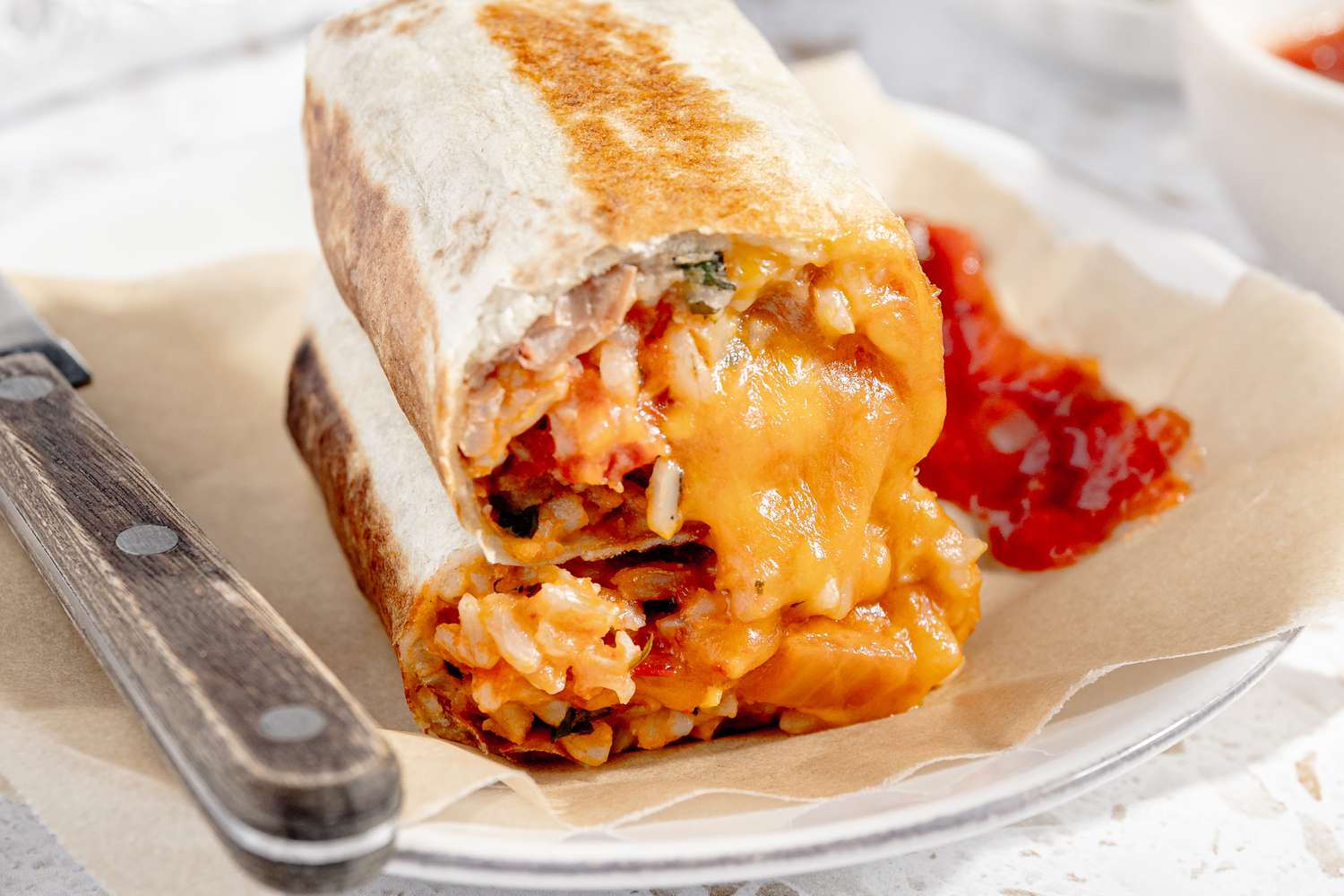 Easy Rice and Beans Freezer Burritos Stacked Together on a Plate With a Table Knife and Salsa 