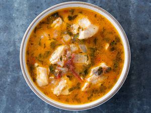 Fish stew in a white bowl on a gray table 