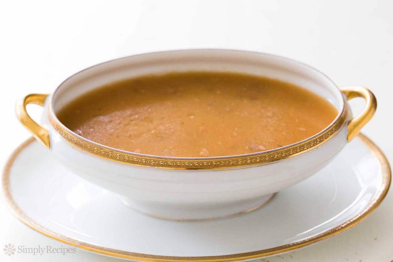 A bowl of gravy resting on a matching plate