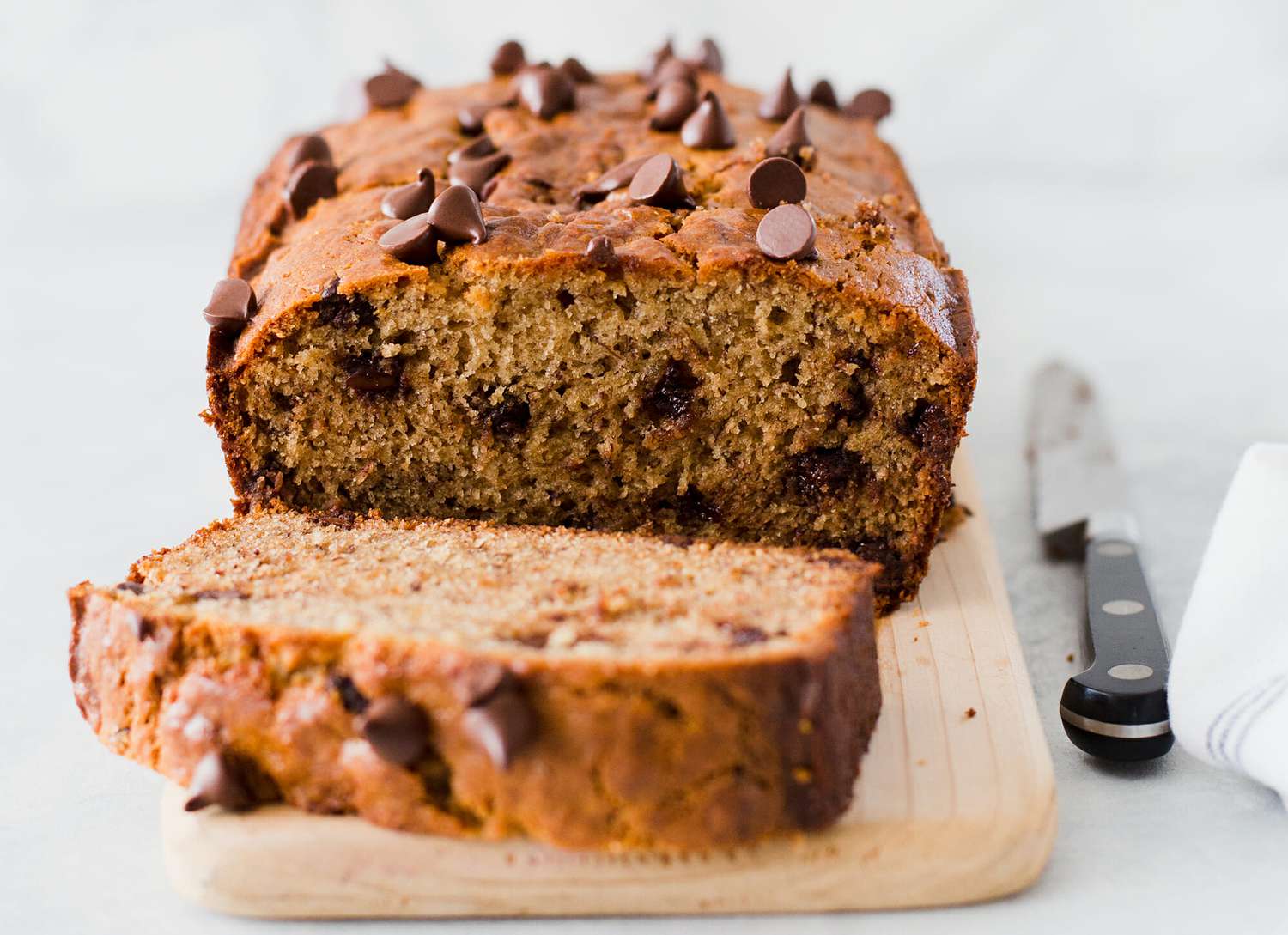peanut butter chocolate chip banana bread on cutting board with knife next to it