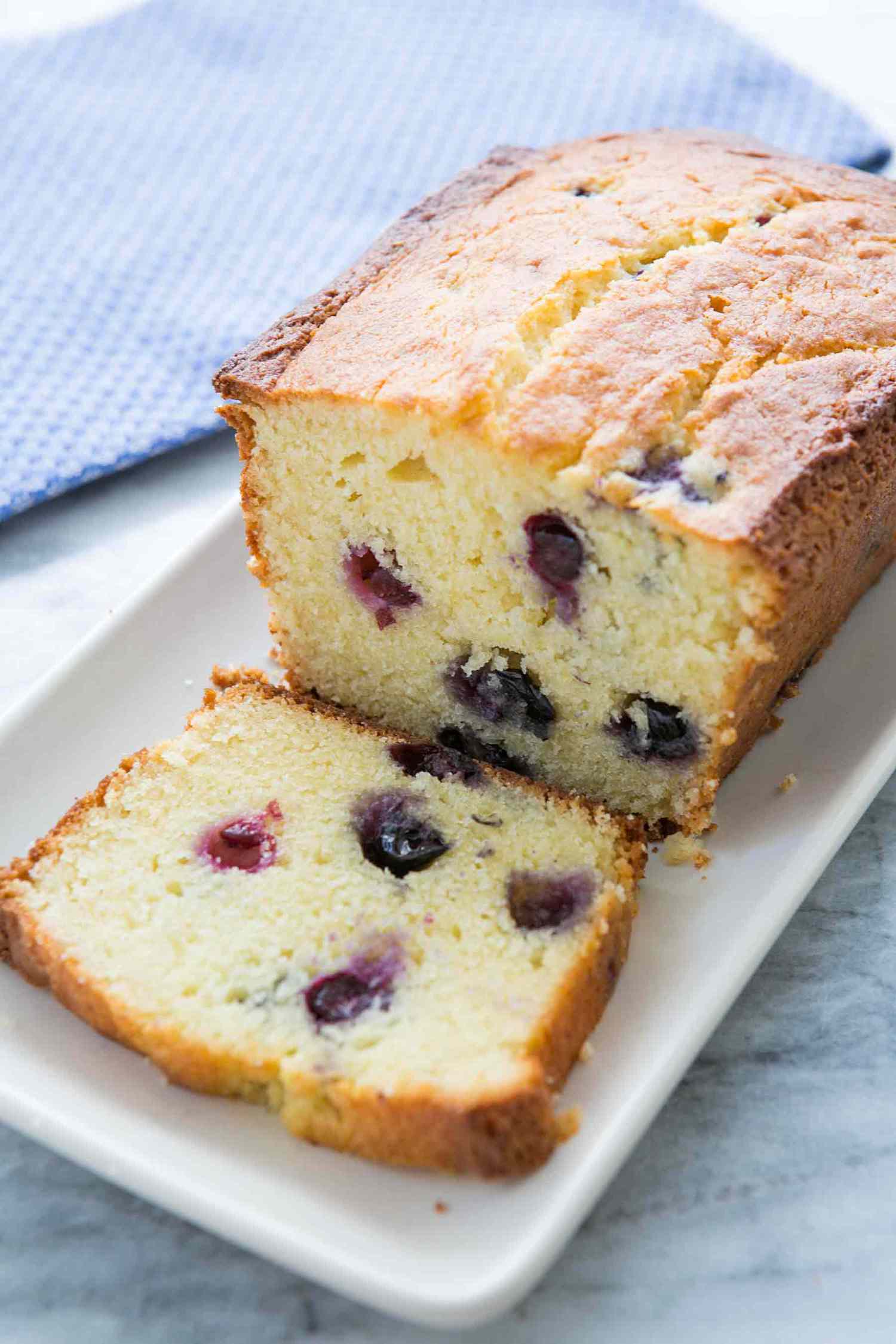Blueberry lemon ricotta pound cake on a white plate with one slice