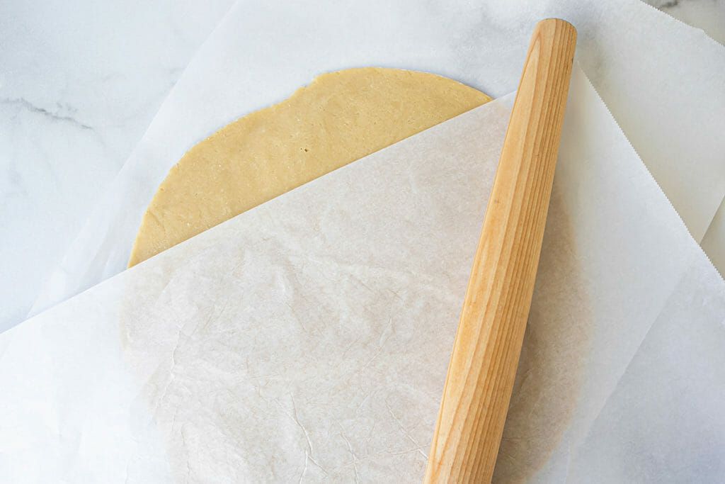 rolling out cookie dough between parchment paper
