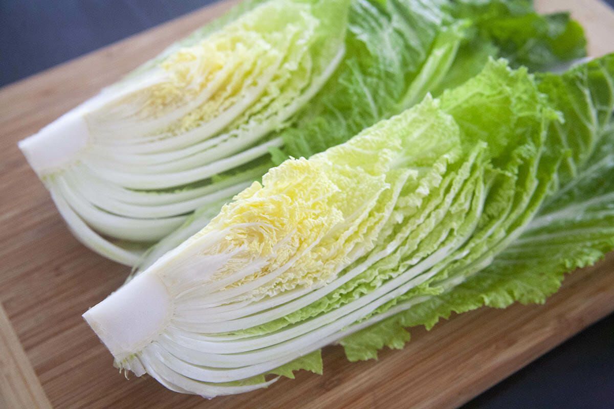 Napa cabbage cut in half on a cutting board for a Korean kimchi recipe.