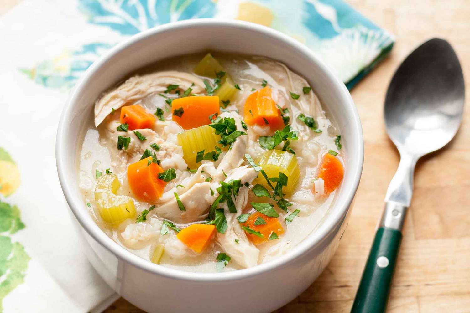 A bowl of One-Pot Chicken and Rice Soup with a spoon and a napkin to the side