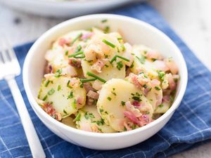 Warm German Potato Salad served in a bowl on a cloth mat with a fork