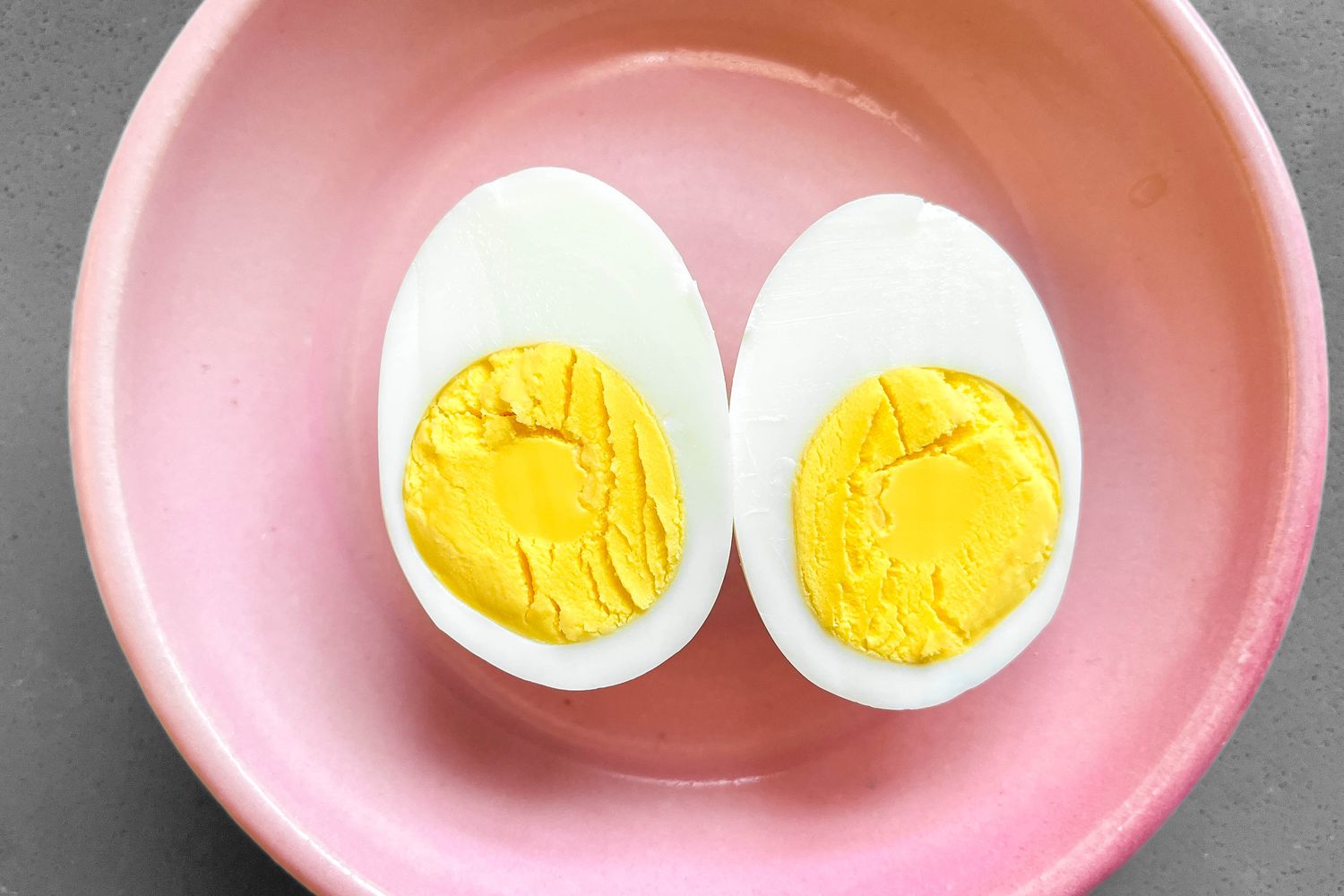A hard boiled egg, cut in half on a small pink plate