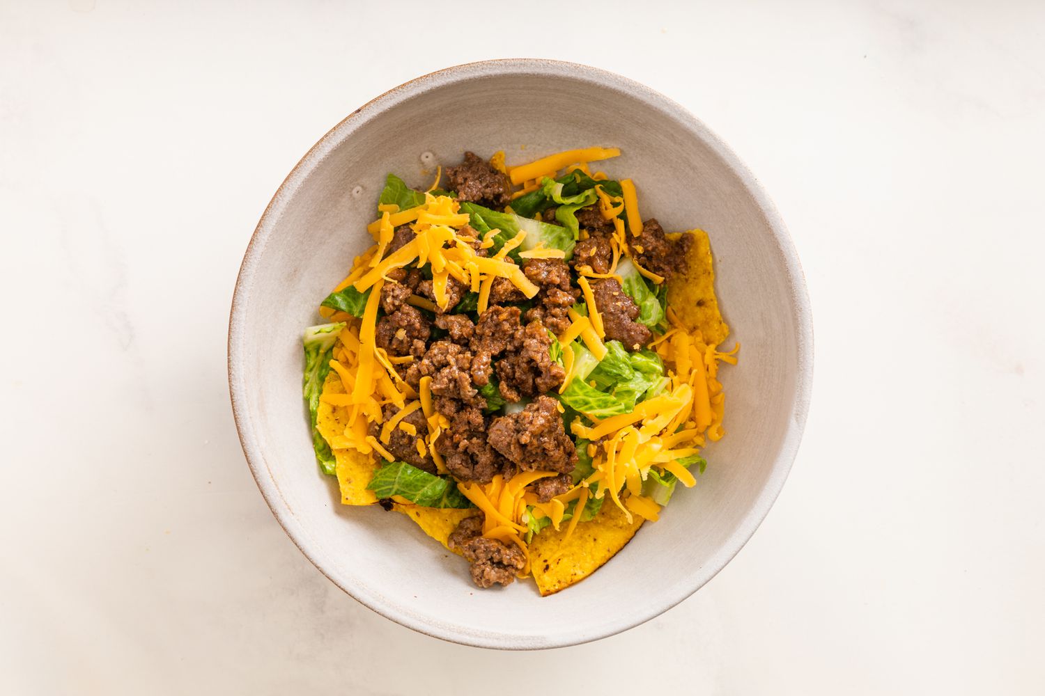 Next, Cooked Ground Beef and Shredded Cheese Added to Bowl 