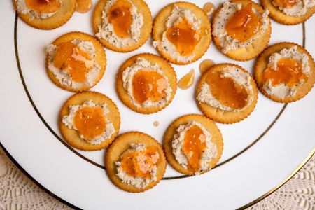 Overhead view of a white plate of Ritz crackers topped with Boursin cheese and mango chutney (Ami's 3-Ingredient Appetizer)