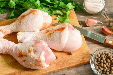 3 seasoned raw chicken legs on a cutting board