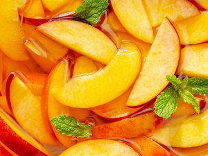 Sliced peaches and mint in a liquid, a fruit preparation for a recipe