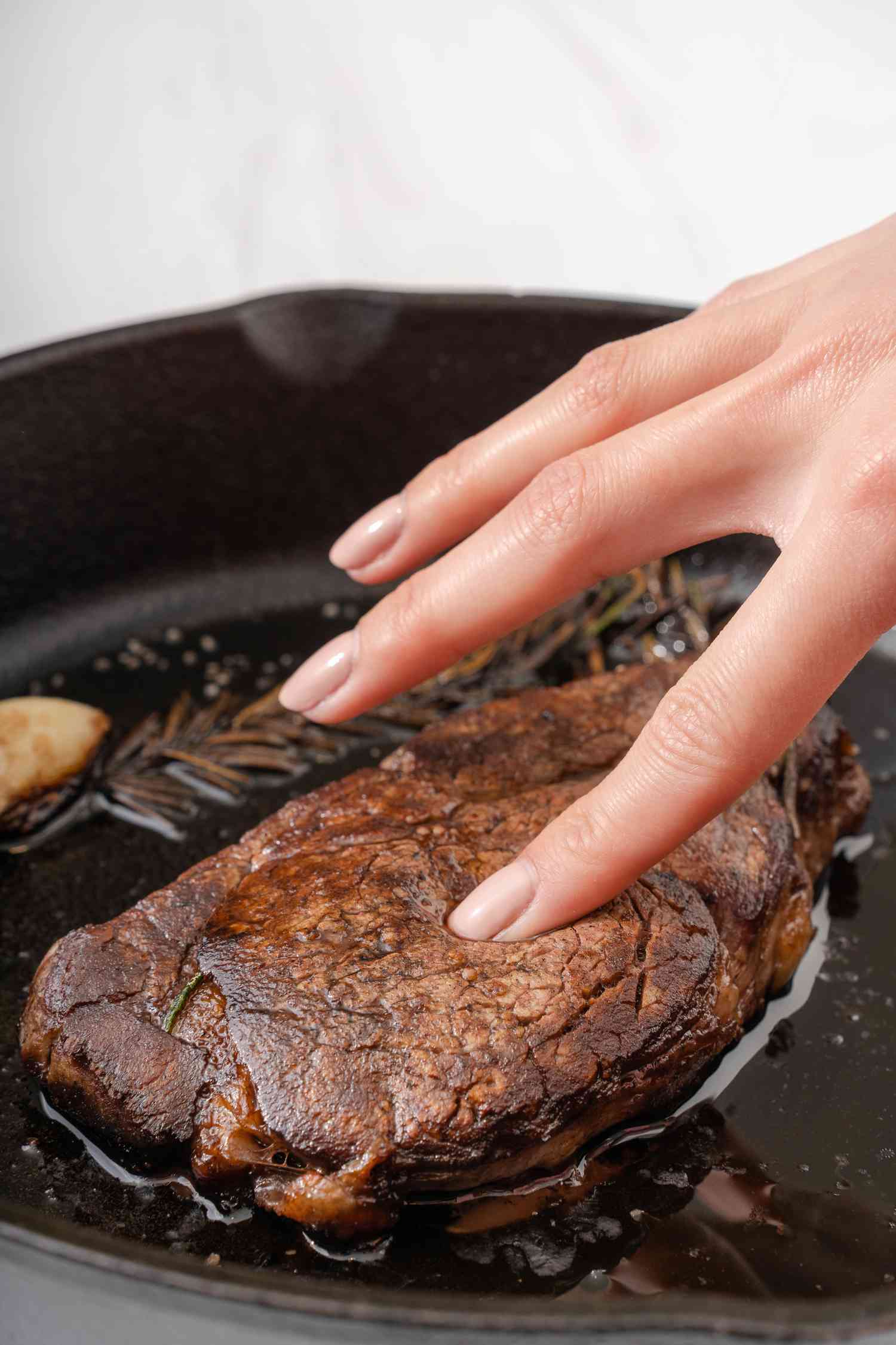 The Finger Test to Check the Doneness of Meat cooking in a skillet