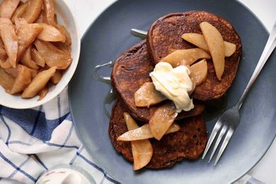 Christmas morning pancakes spread on a plate and topped with pears and creme fraiche. Additional pears are in a bowl next to the plate.