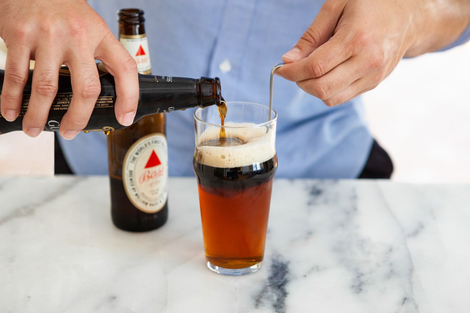Bottle of Stout Carefully Poured into Glass of Black and Tan