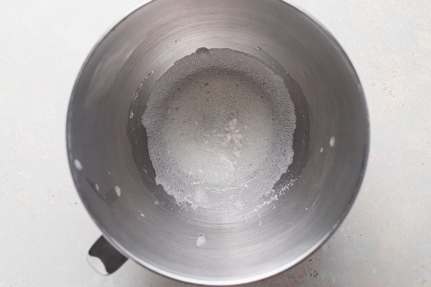 Whisking egg whites in the bowl of a stand mixer to make French macarons with peppermint white chocolate filling