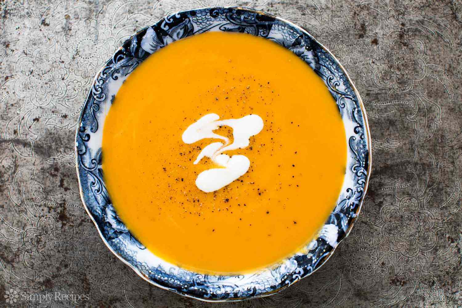 A bowl of pureed sweet potato soup with a garnish of sour cream