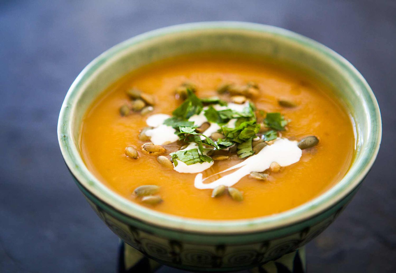 A bowl of Chipotle Pumpkin Soup garnished with pumpkin seeds, cilantro, and sour cream