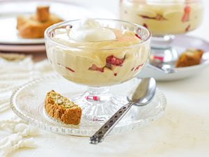 Two parfait glasses with a custard dessert topped with cream and layered with strawberries.