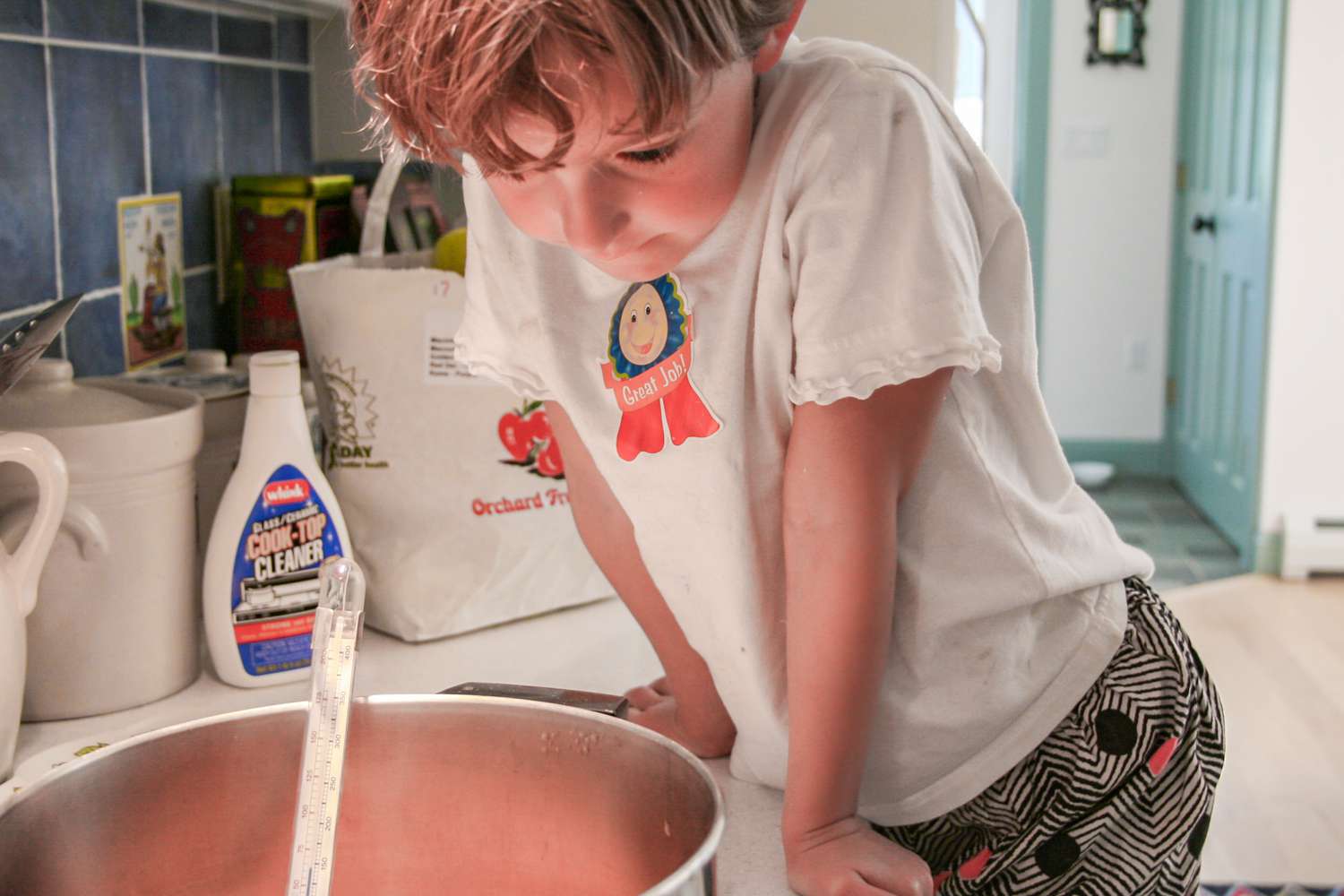 A young child peers into a pot of cooking quince jelly