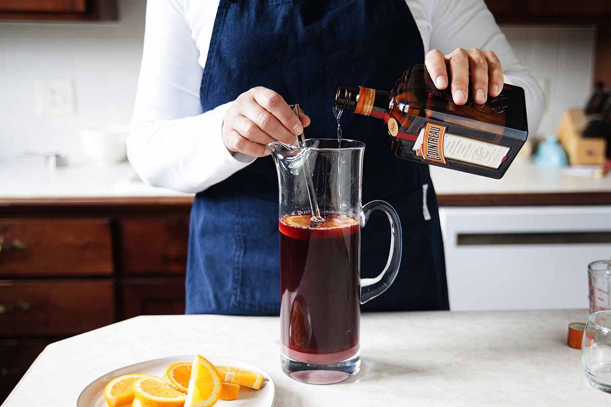 How to Make Sangria - orange slices in a pitcher of sangria on a silver tray with two poured glasses of sangria