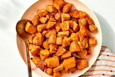 Overhead view of a bowl with cubes of roasted sweet potato along with a metal spoon