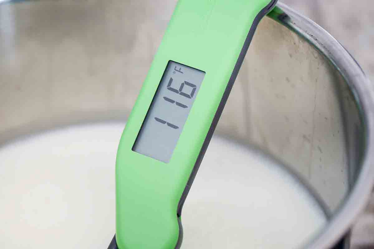 A thermometer checking the temperature of the milk in a pressure cooker