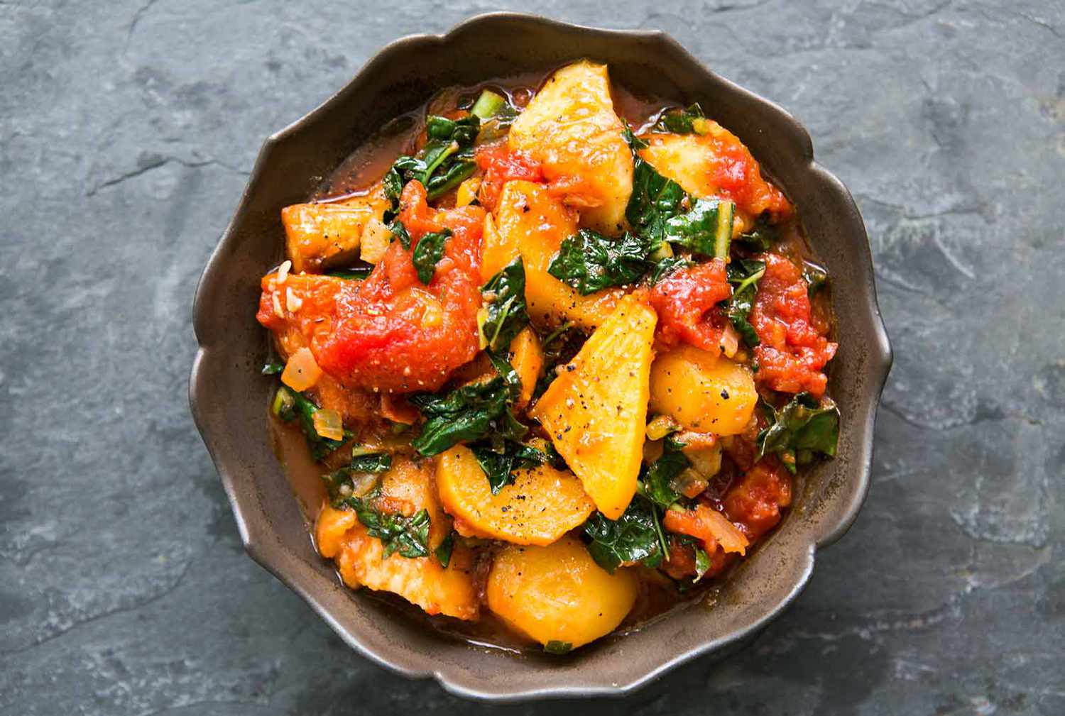Roasted root vegetables with kale and tomatoes in a bowl