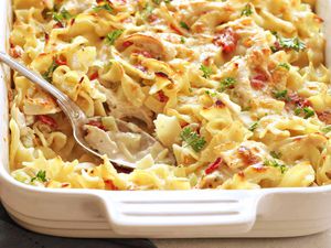 Creamy Chicken Noodle Casserole in a white baking dish with a silver spoon.