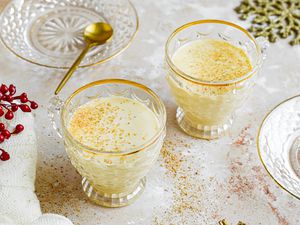 Two gold-rimmed glasses of eggnog cocktail.