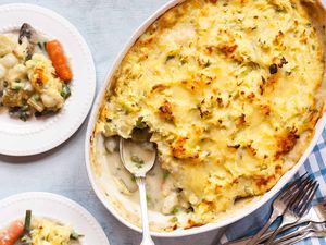 Vegetarian Shepherd’s Pie Recipe -- top down shot of shepards pie scoop taken out, golden and crispy edge mashed potatoes on top. Blue check table cloth, and a plate with some sheperd'e pie serve on top of it.