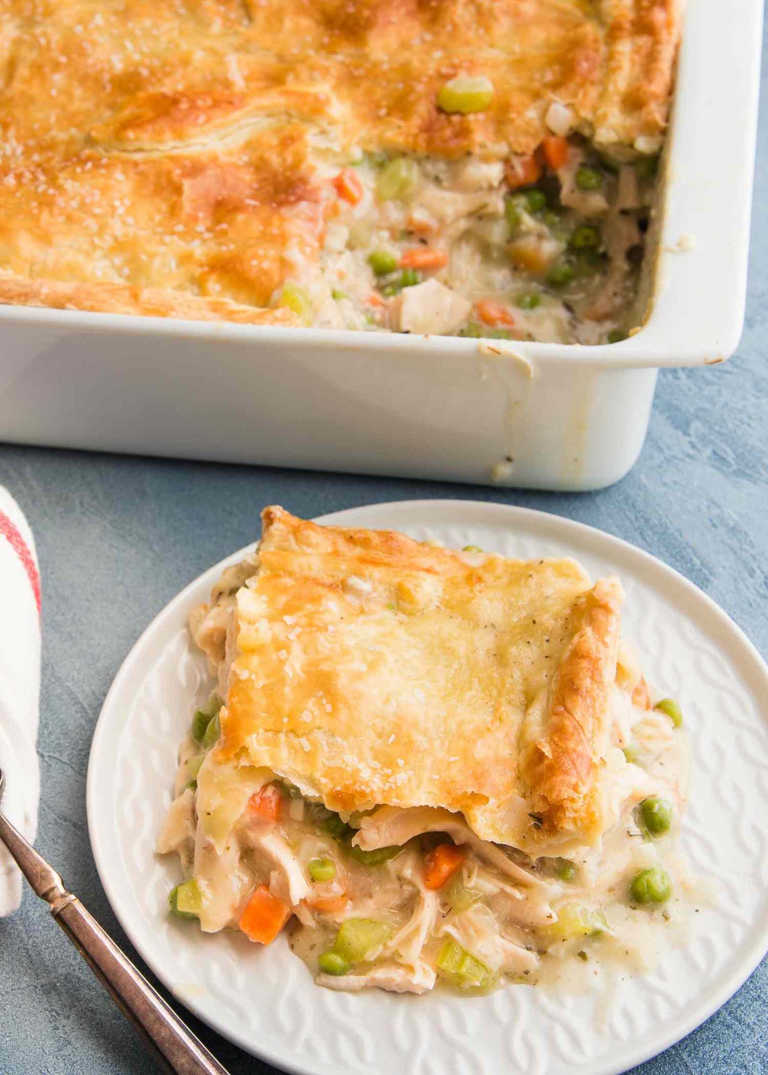 The best Chicken Pot Pie is on a plate and the rest of the casserole is set behind it.