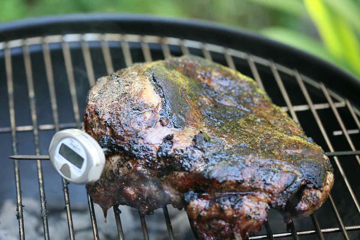 butterflied leg of lamb on grill with thermometer in it