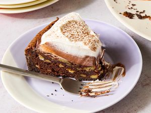 Closeup of a small multicolored plate with a slice of Mississippi Mud Pie with a fork next to a plate of the pie with several slices removed and a stack of empty plates