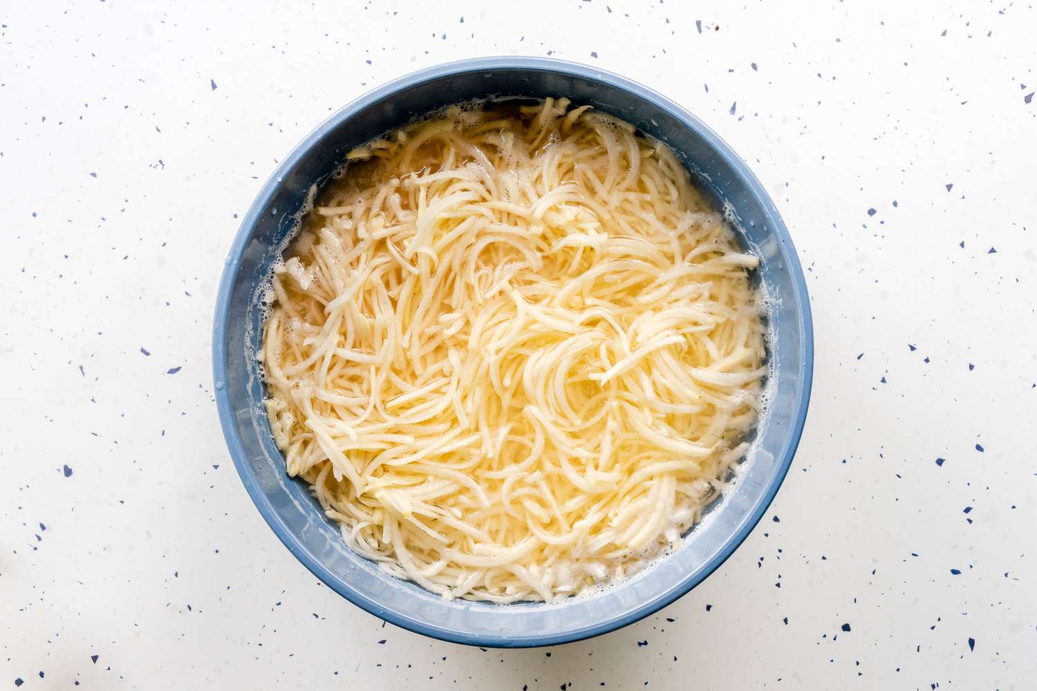 Grated Potatoes Soaking in a Bowl of Water for Kugel Recipe