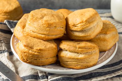 A white plate with buttermilk biscuits stacked high