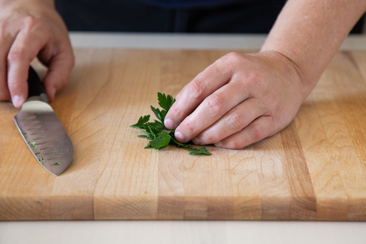 Holding a pile of parsley leaves next to a chef's knife