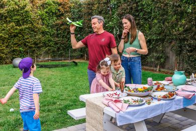 The Pfeffer parents and their three children play outside alongside a table of food