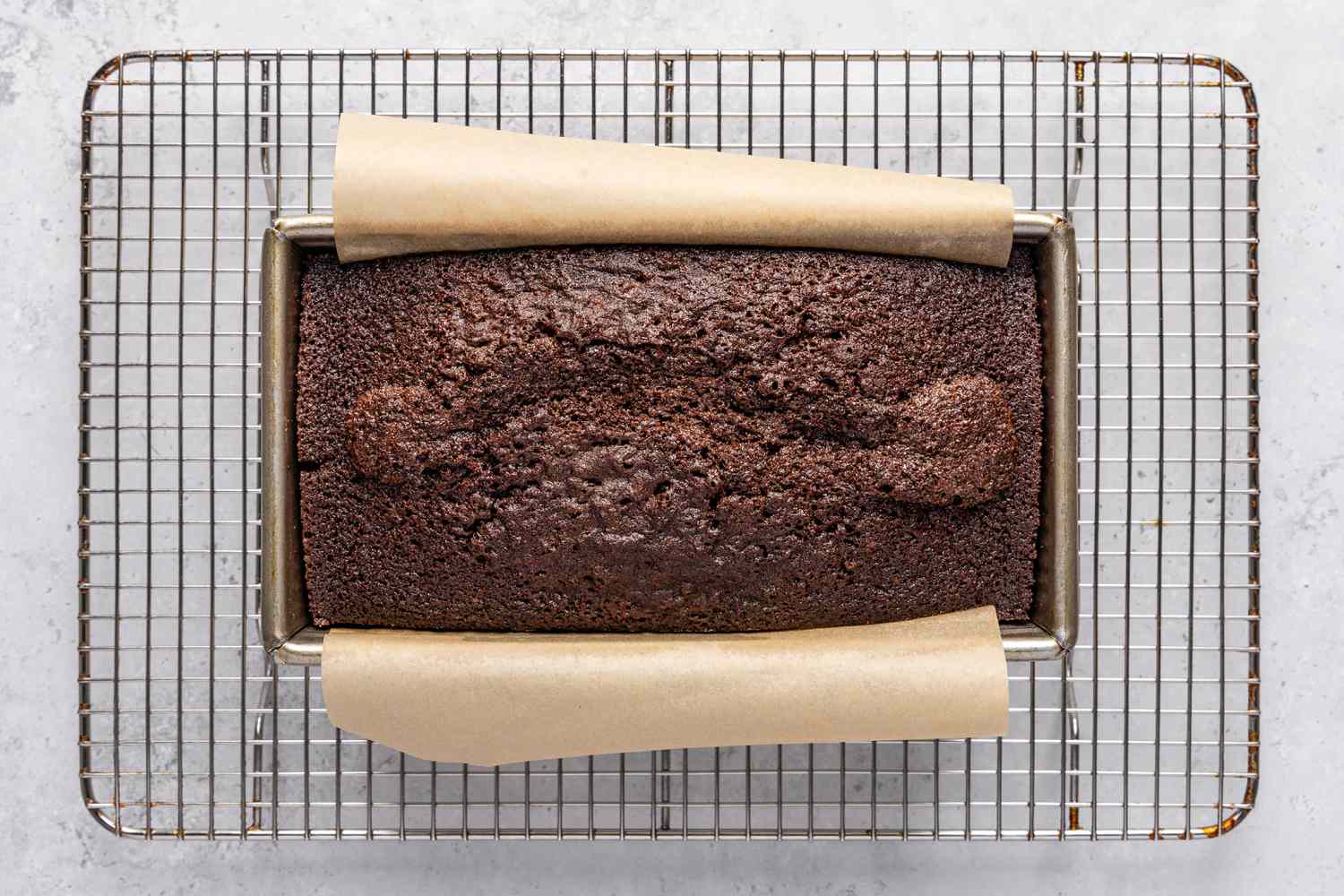 The baked chocolate stout loaf cake in a baking pan on a cooling rack