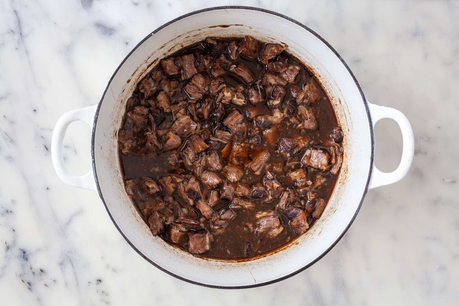 Meat added back into the braising liquid to show how to cook oxtails.