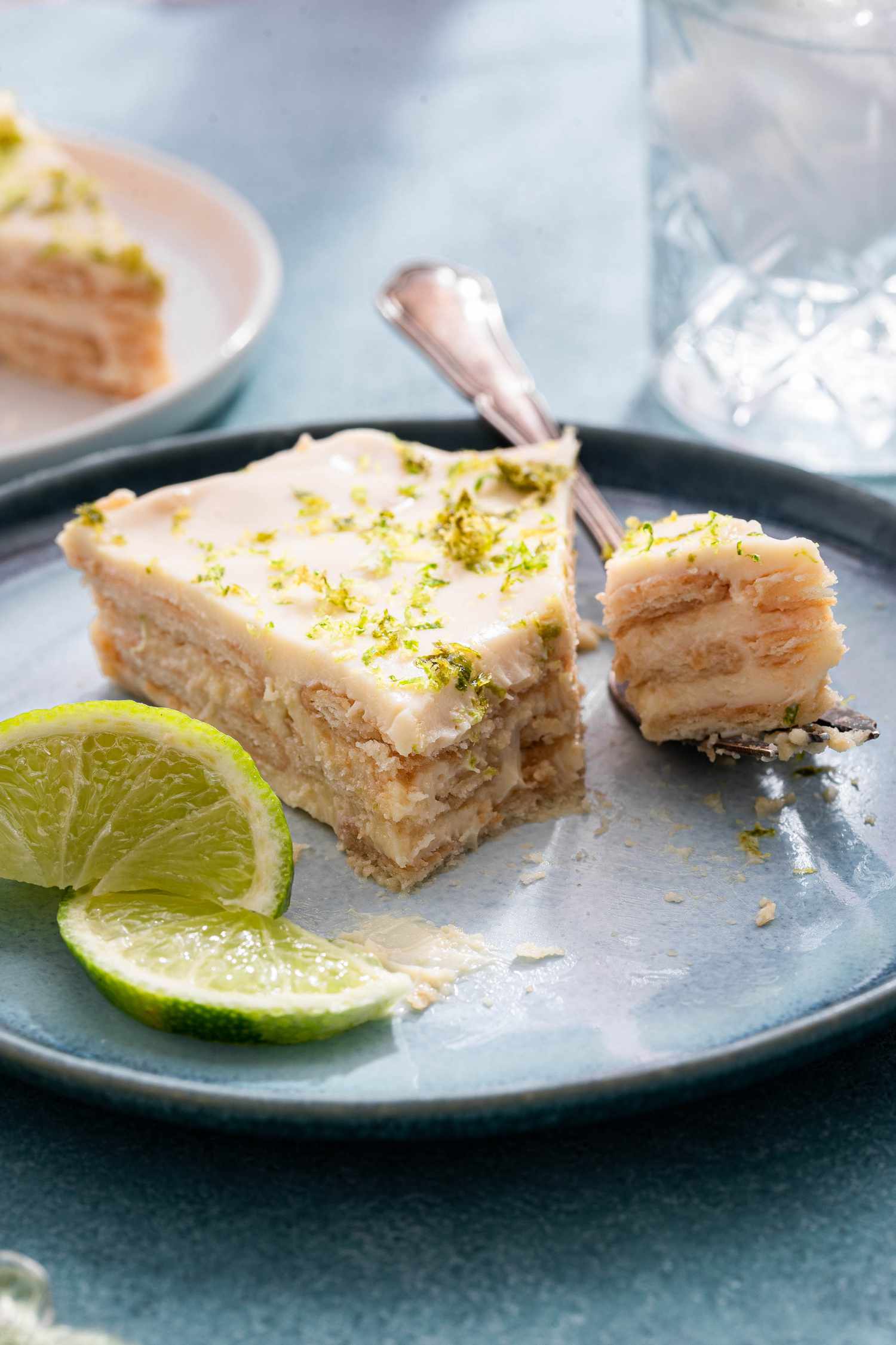 Lime icebox cake slice in a blue plate with a bite on a fork